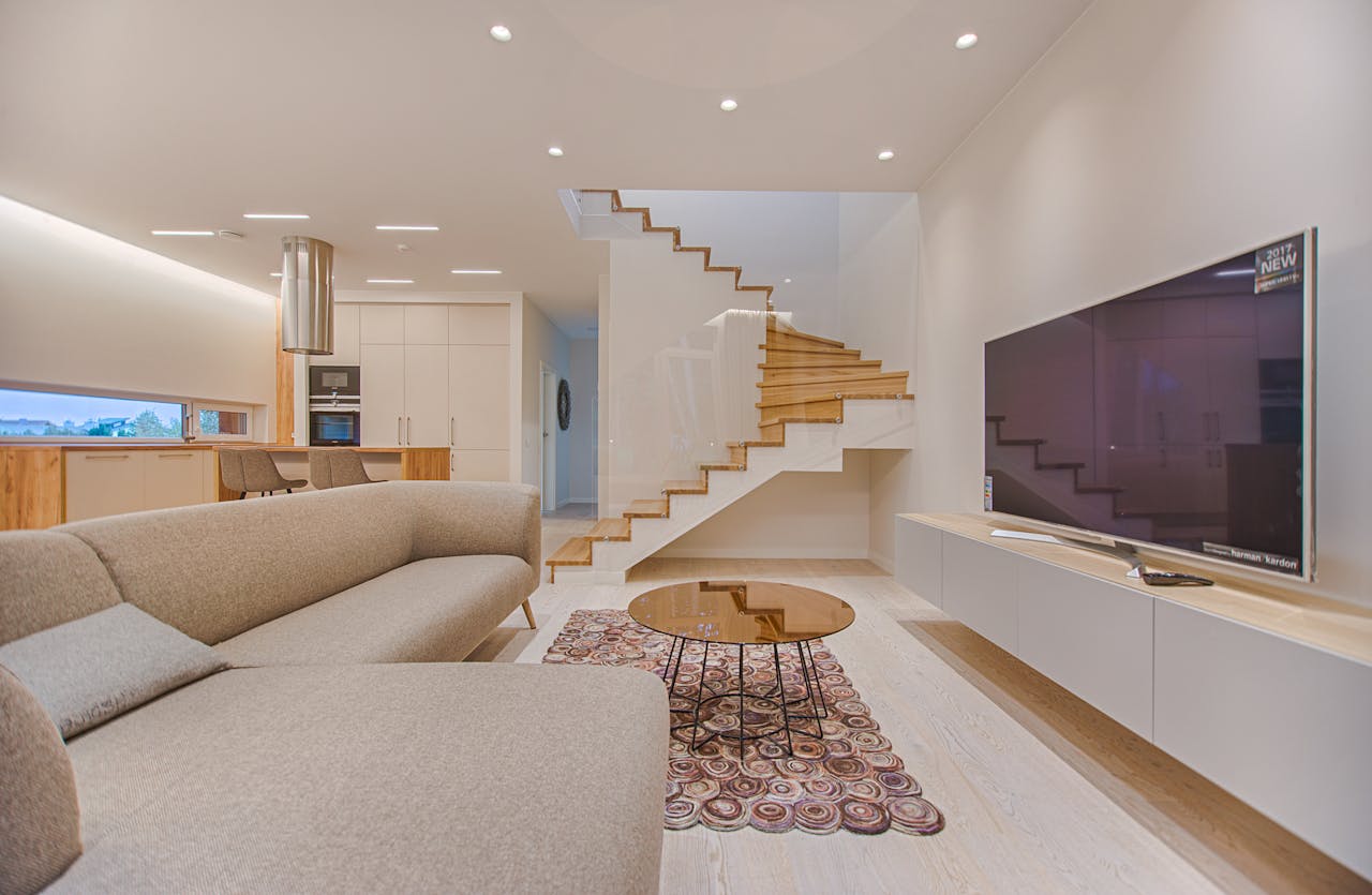 about-img-02 Spacious modern living room featuring stairs, a TV, and sleek furniture design.